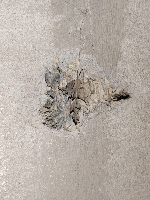 Skadad puts på en yttervägg med synliga porösa och sönderfallande materialskikt inunder, i ett lättbetong-hus från 1964.