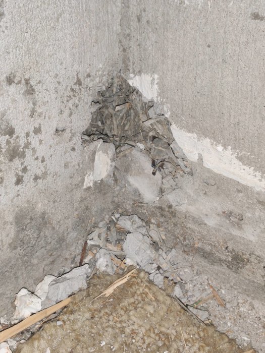 Skadad yttervägg med hål och poröst material, rester av puts och träspån synliga efter rivning.