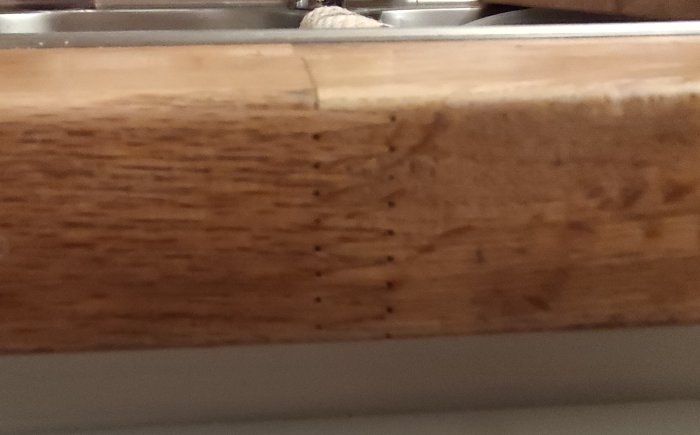 Närbild på en massiv ek-skiva med synliga skarvar, liknande äldre Ikea-produkt.