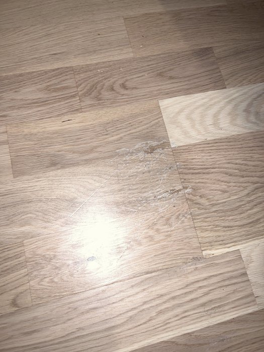Parkettgolv med synliga repor och slitage i ytlacket.