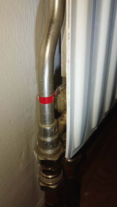 Radiatorkoppling med justerskruv och rör som föreslår en enrörsslinga i en bostad.