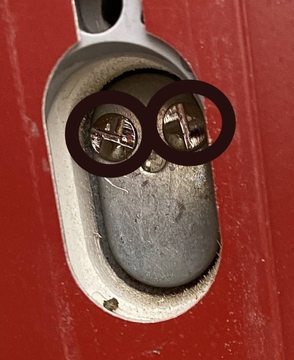 Envägsskruvar i låscylinder på röd dörr, metoder för att ta bort skisseras i text.