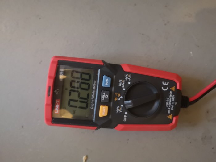 Digital multimeter som visar 0.00 V på displayen ligger på en grå yta.