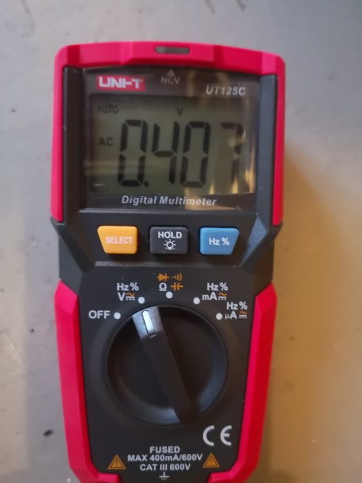 Digital multimeter visar en spänning på 407 volt.