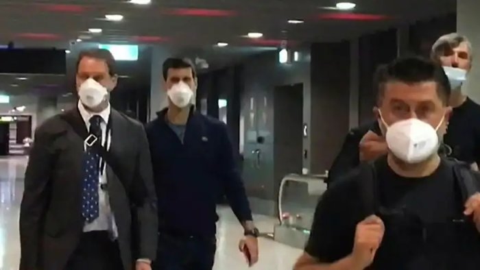 Personer med skyddsmasker går genom en flygplats terminal.