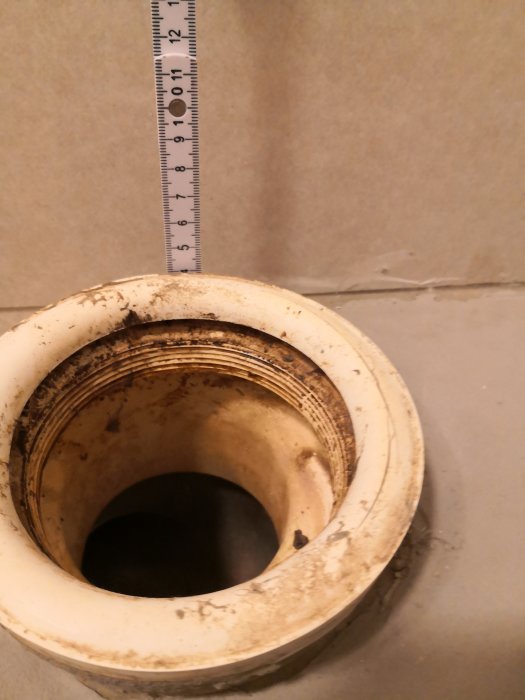 Måttband visar att toalettstosens öppning sticker upp cirka 4 cm från golvet.