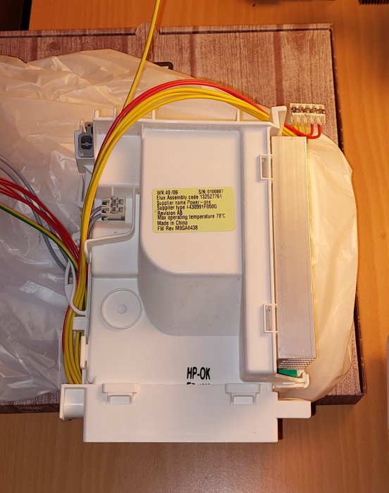 Omriktare med kablar och etiketter synlig på en träyta och en delvis synlig plastpåse.