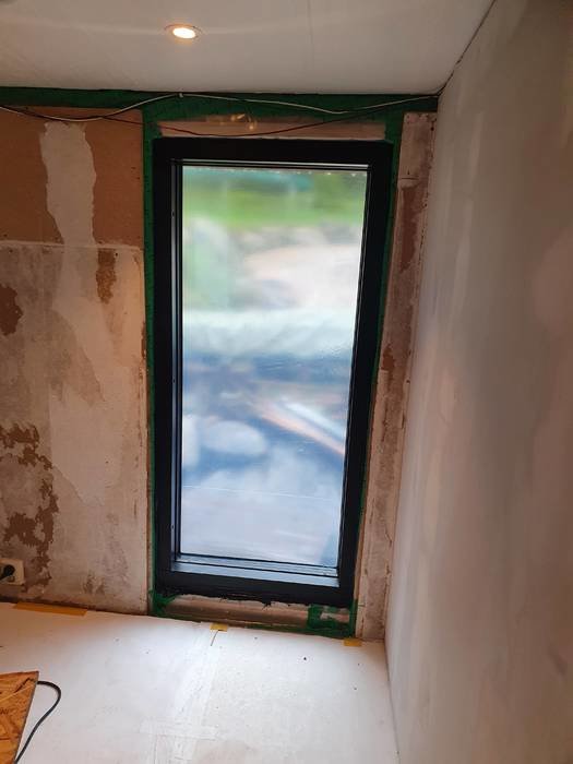Nytt golv-till-tak-fönster installerat i en renoverad hall, väntar på slutlig inredning och finish.