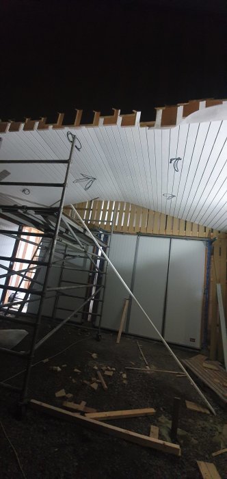 Nyligen installerat vitt innertak i carport med synliga balkar och byggställning.