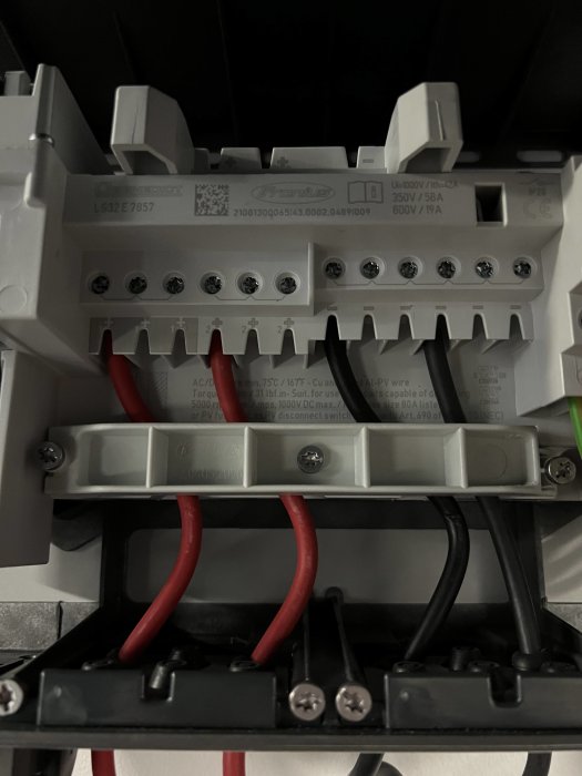 Närbild av en elcentral med etiketter och anslutna röda och svarta kablar, antydan om potentiell diagnos för strömavbrott.