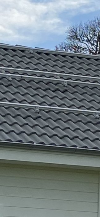 Tegeltak efter montering med synliga takkrokar och solpanelsskenor på husets övre del.