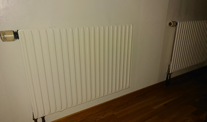 Två vita värmeelement på en vägg intill varandra, det vänstra är tyst och det högra låter.