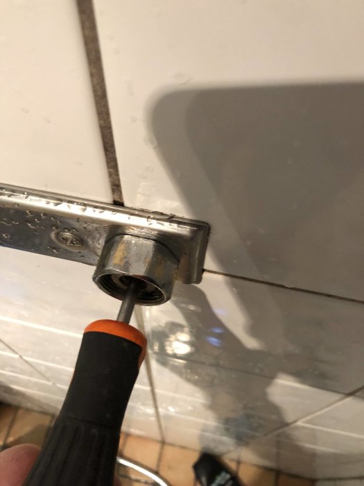 Skruvmejsel insatt i ett rör av en duschblandare med droppar av vatten, indikerar eventuellt stopp.