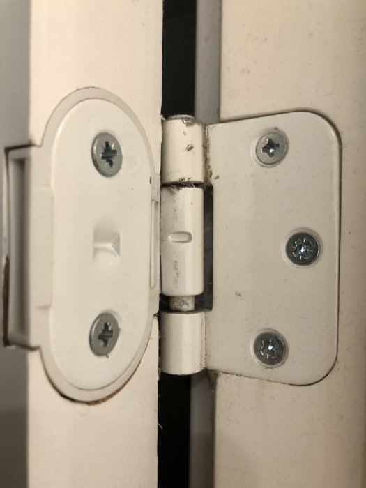 Close-up på vit dörr och dess gångjärn med möjlig inkorrekt monterad bricka.