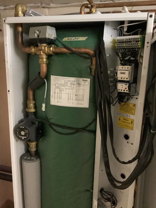 Värmepumpsinstallation med rörkopplingar, elskåp och inställningsdiagram.