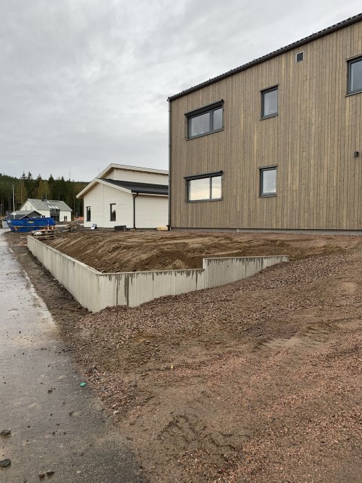 Nybyggt hus med stödmurar för trädgården och pågående markarbeten på en molnig dag.