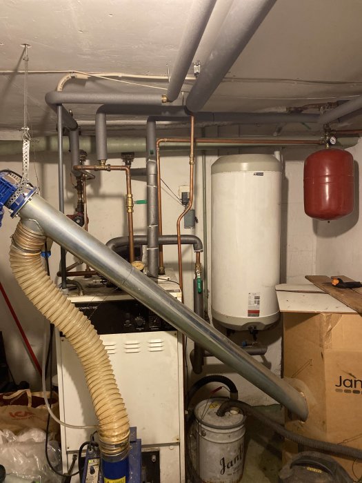 Pannrum med pelletspanna, ackumulatortank, rör och kranar, används i diskussion om värmesystemproblem.