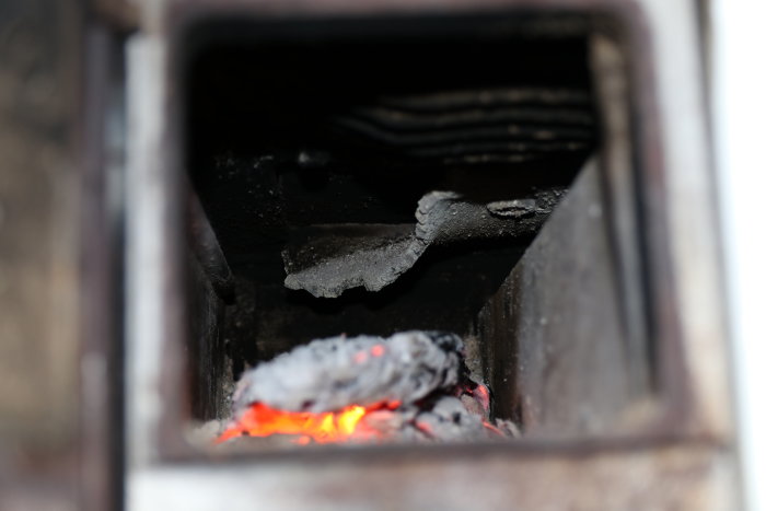 Vedeldad kamin med trasig och vriden inre del synlig genom eldstadens öppning.