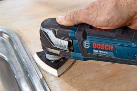 En hand som använder en Bosch deltaslipmaskin för att slipa en trälist.