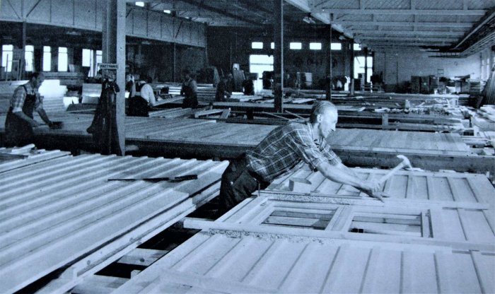 Svartvit bild på arbetare som tillverkar fönster i en fabrikshus från tidigt 80-tal.