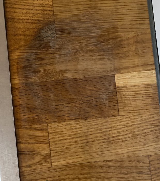 Närbild på ett mörkbrunt trägolv med synliga plankor och ådringar.