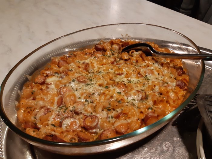 Gratäng med makaroner, korv och smält ost i ugnssäker form, redo att serveras.