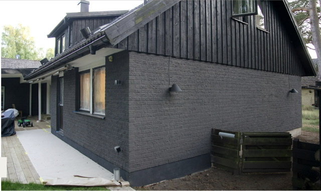 Exteriör av ett hus med mörkgrått tegel och svarta fönsterkarmar från 2013.