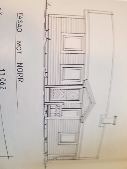 Arkitektskiss av en byggnadsfasad mot norr med detaljerat ritade fönster, dörrar och sadeltak.