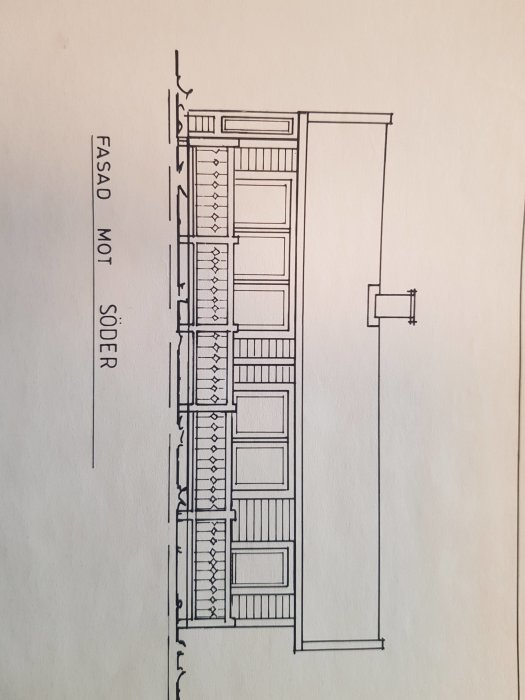 Fasadritning av en avlång byggnad med många fönster på den sidan som är vänd mot söder.