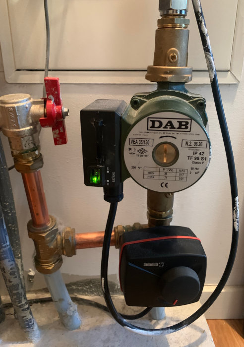 Golvvärmesystem med pump och shunt, justeringsrattar och anslutna rör.