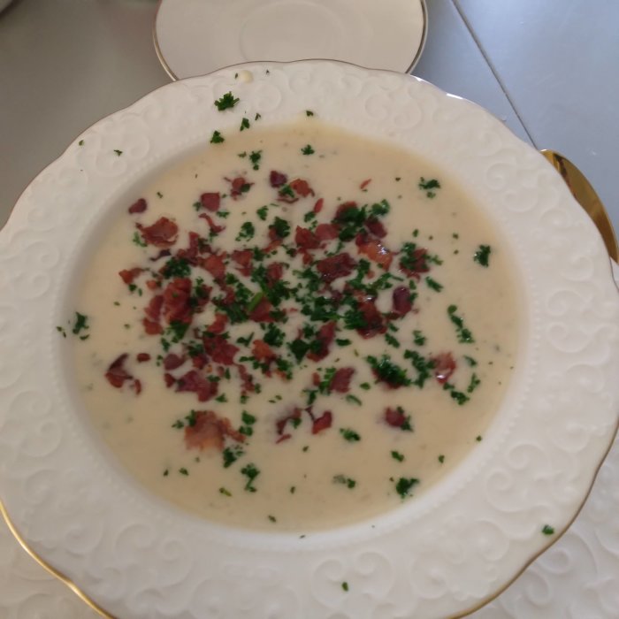 Tallrik med krämig jordärtskockssoppa toppad med bacon och hackad persilja.