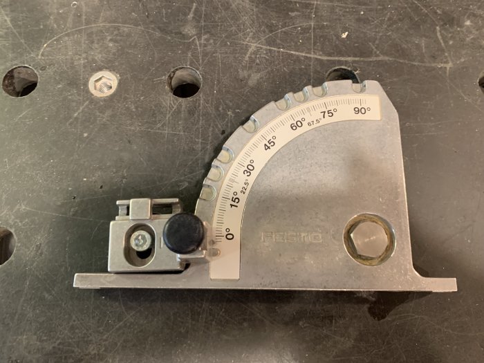 Vinkelanslag från Festool med gradering och ställbar fastsättningskloss på en sliten svart arbetsyta.