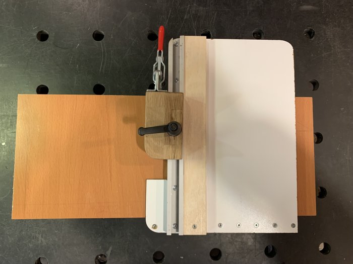 Handgjord kapjigg av masonit med ställbar fastsättningskloss för precisionssågning.