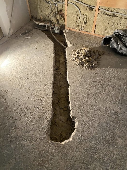 Uppbruten betonggolv i ett rum för installation av vatten/avlopp inför köksö.