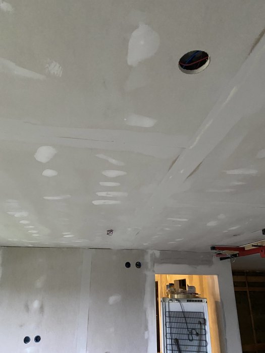 Renoveringsarbete med slätspacklade väggar och tak med synliga kabelförberedelser för köksön.