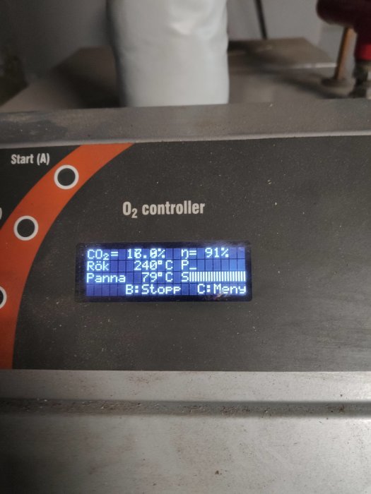 Digital display på en O2-kontrollenhet som visar rökgasvärden och pannans temperatur.