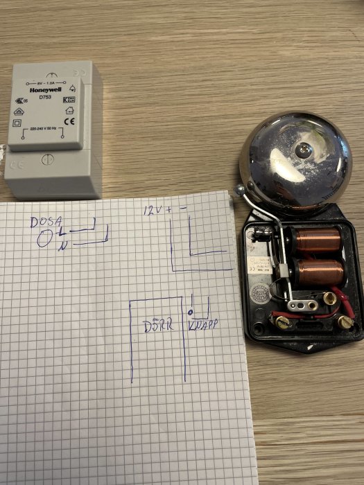 Transformator och gammaldags ringklocka med öppet lock bredvid skiss på anslutning.