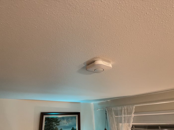 Google Nest Protect brandvarnare installerad på ett vitt tak i ett rum.