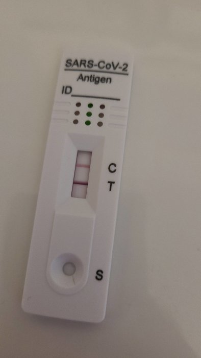 Positivt COVID-19 antigentest som visar två röda streck vid C och T.