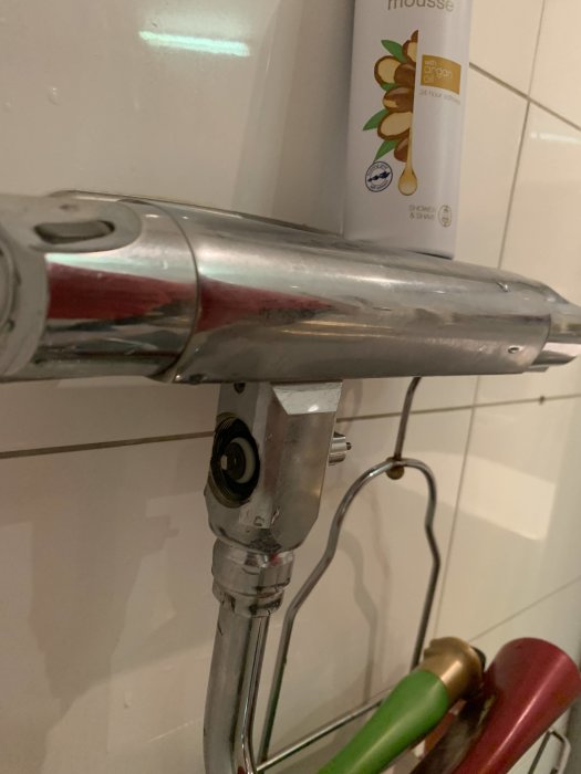 Närbild av en ca 10 år gammal, troligen Gustavsberg, duschblandare med synliga gängor och anslutning för duschen.