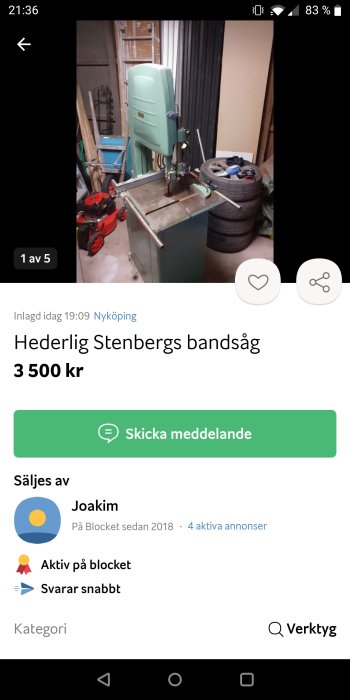 Grönt band-såg verktyg i garage med sågblad, skyddslock uppfällt, omgivet av olika föremål och redskap.