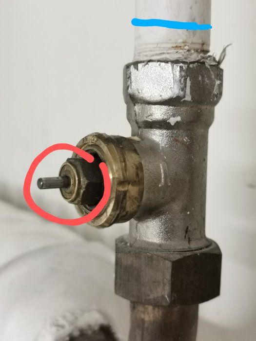 Close-up på en radiatorventil med röd cirkel runt insatsen och ett blått streck på röret som markerar diameter.