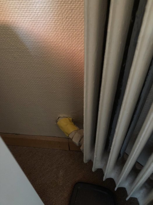 Radiator utan strypningsmöjlighet med synliga röranslutningar mot vägg och golv.