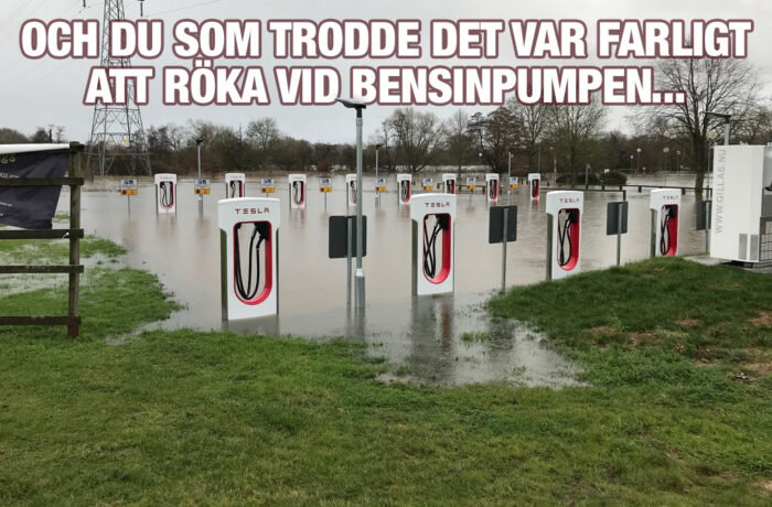 En översvämmad Tesla-laddstation med vatten upp till laddningsenheter, ironisk text om rökning vid bensinpumpar.