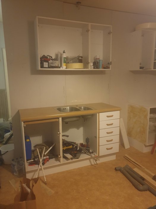 Köksrenovering med delvis installerad bänkskiva, diskho och verktyg på golvet.