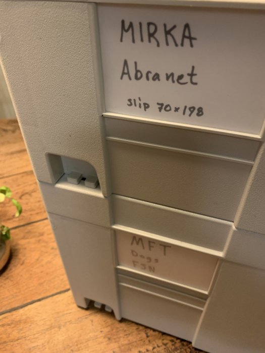 Plastlåda med etiketter för verktyg, "MIRKA Abranet" och "MFT" synligt på lådfronterna.