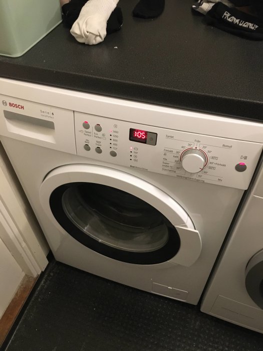 En välfungerande Bosch tvättmaskin med digital display som visar 0:05 och rena strumpor på toppen.