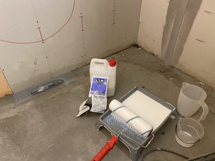 Renoverat golv med mätmarkeringar, primer och rullar redo för arbete.