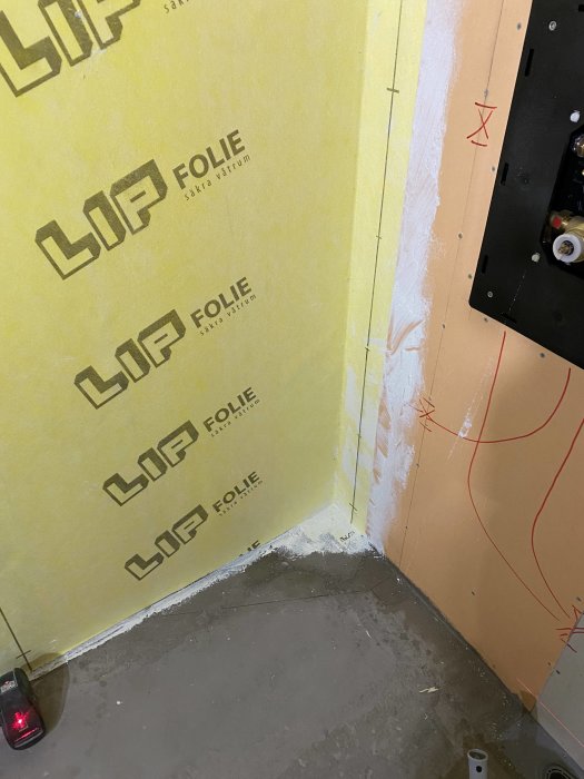 Starten på ett väggnära brunnsinstallation med LIP Folie och primad betonggolv synlig.