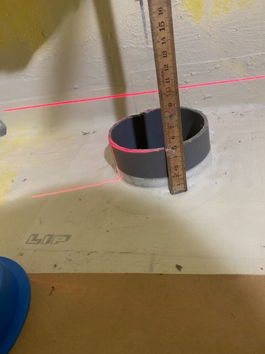 Mätning av toalettavlopp som sticker upp 50mm från golv med en laser och tumstock.